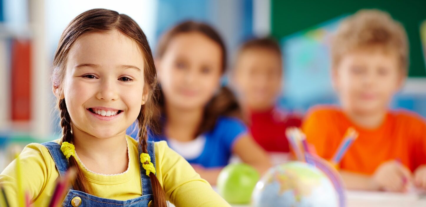 Preschool children smiling in a classroom.
